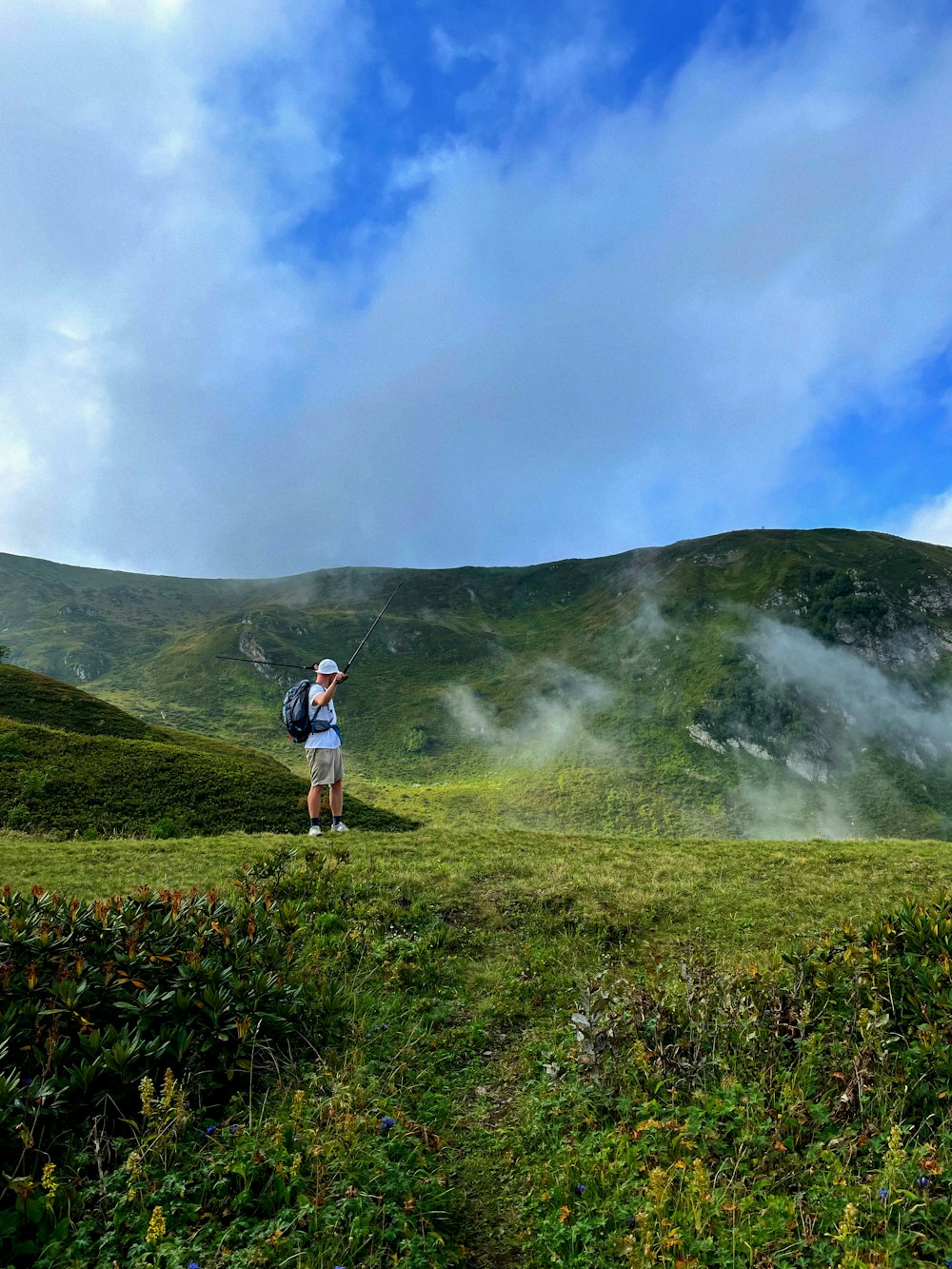 a man standing on top of a lush green hillside