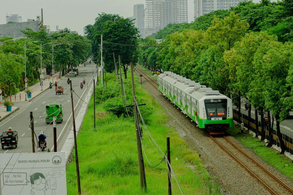 Un treno verde e bianco che viaggia lungo i binari del treno