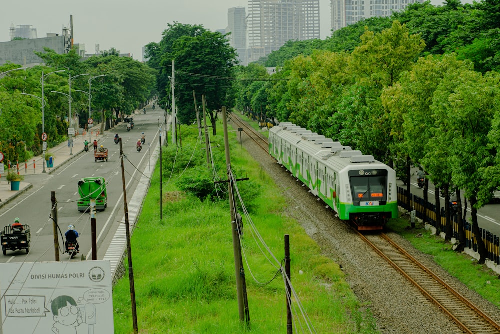 a green and white train traveling down train tracks