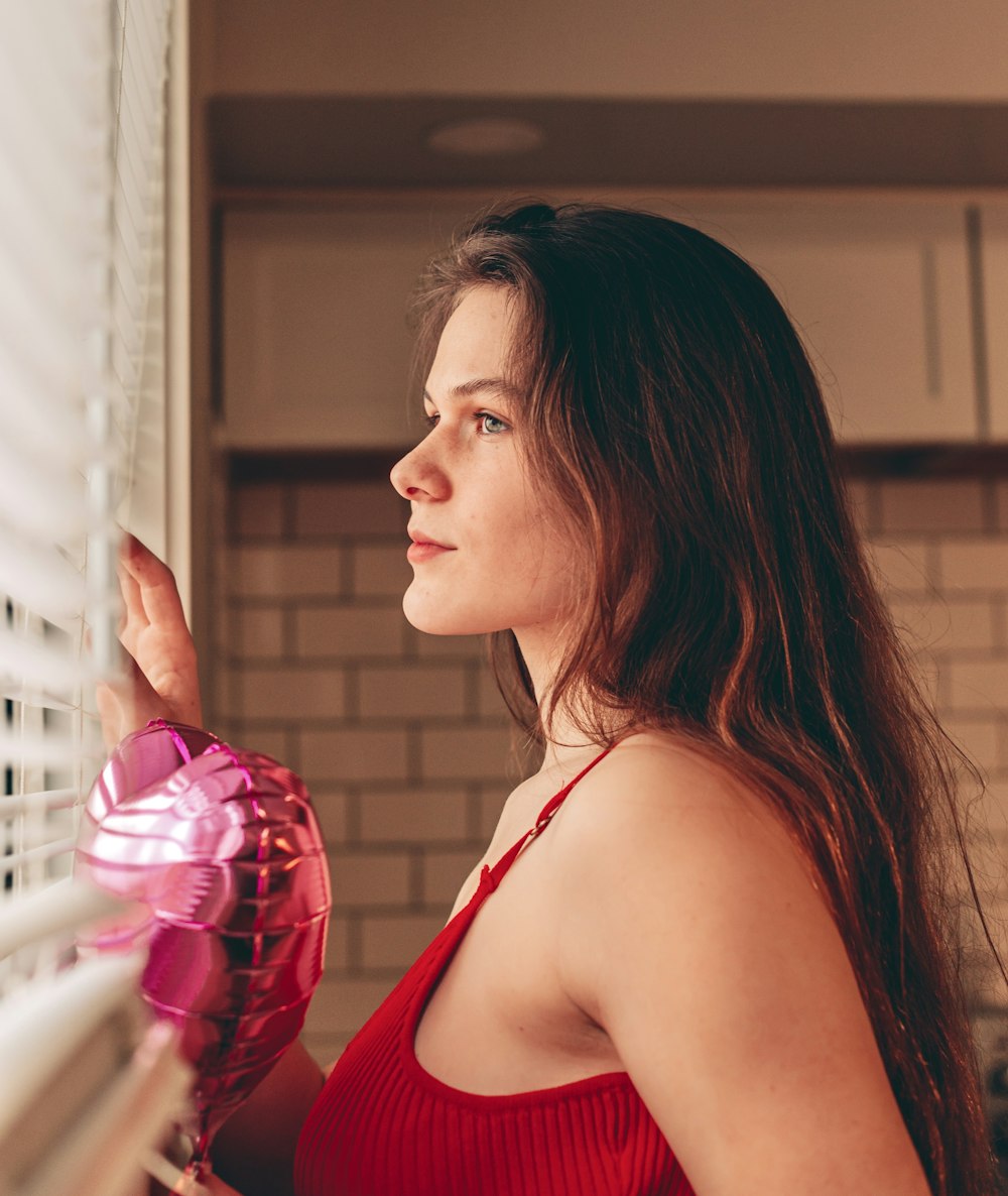 a woman in a red top looking out a window