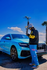 a man standing next to a blue car