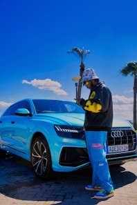 a man standing next to a blue car