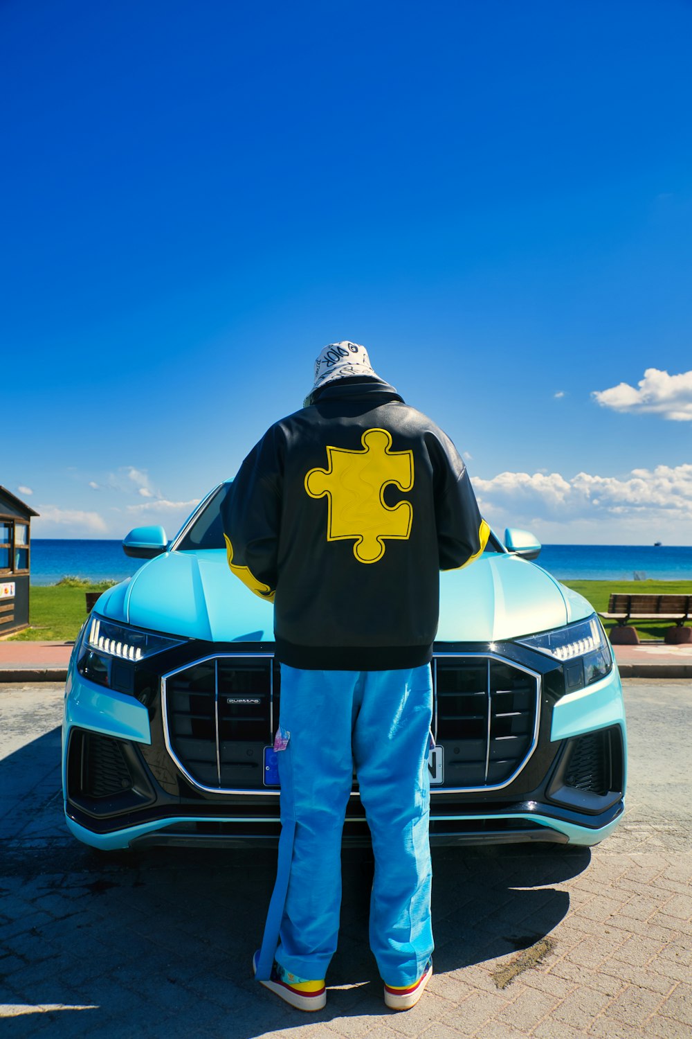 a man standing next to a blue car with a puzzle piece on it