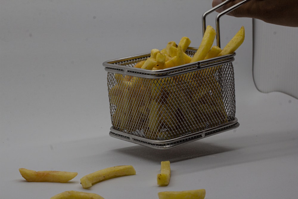 a basket full of french fries with a person picking them