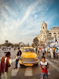 a group of people standing around a yellow car
