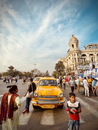 a group of people standing around a yellow car