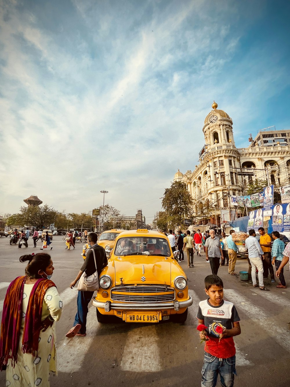 a group of people standing around a yellow car