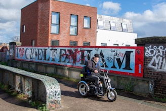 a man riding a motorcycle next to a graffiti covered wall