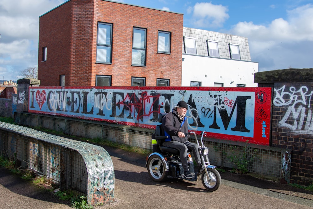 a man riding a motorcycle next to a graffiti covered wall