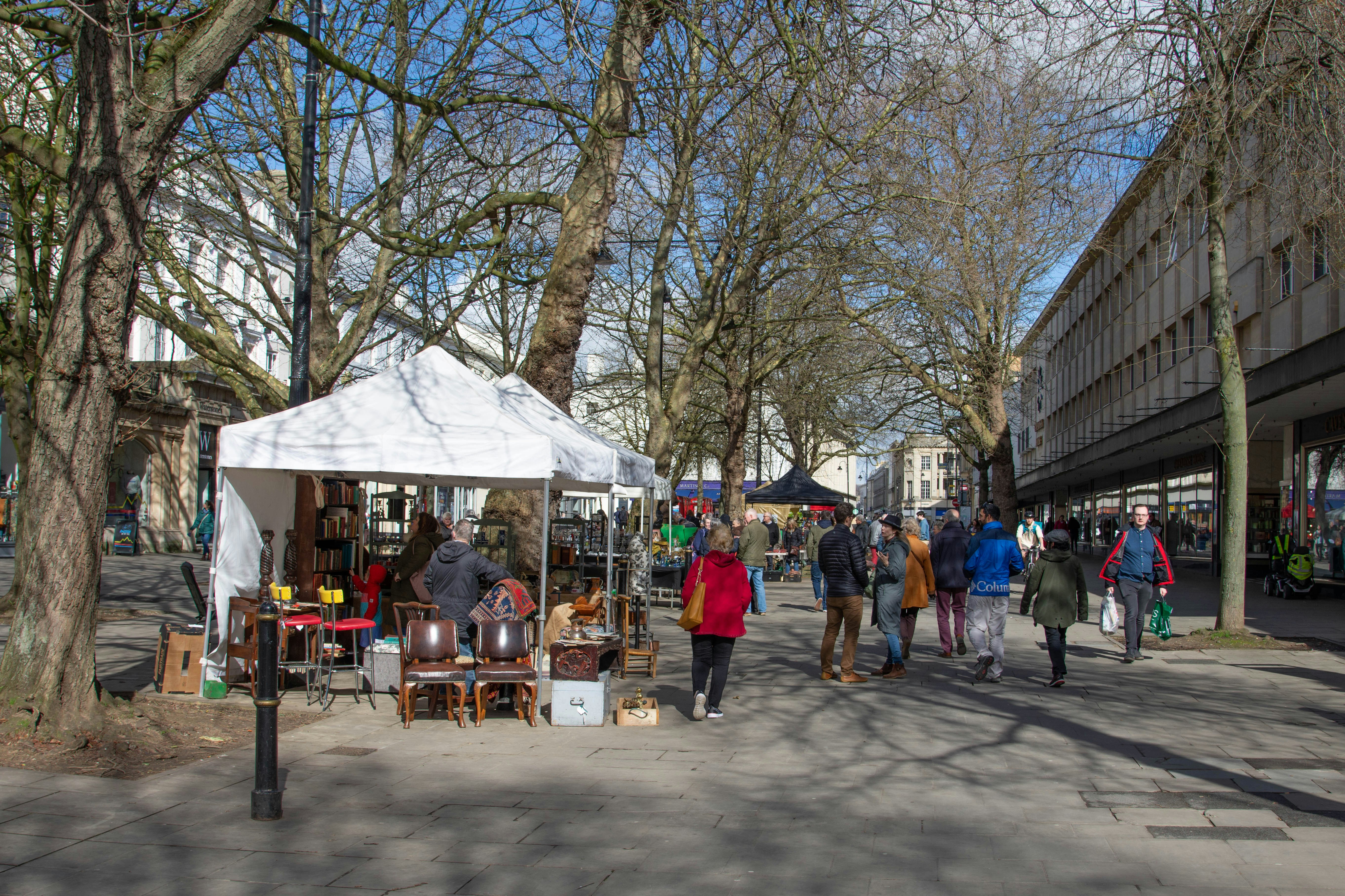 a group of people walking down a street next to a white tent