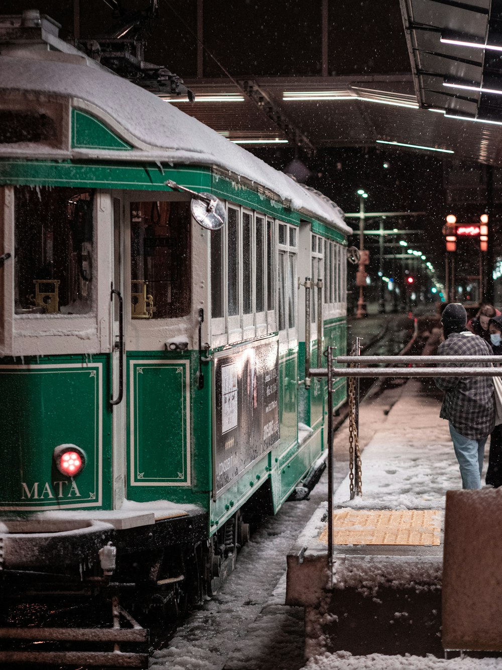 a green and white train pulling into a train station