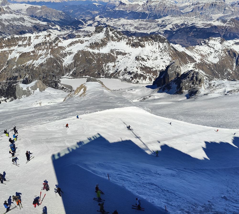 Un grupo de personas montando esquís en la cima de una pista cubierta de nieve