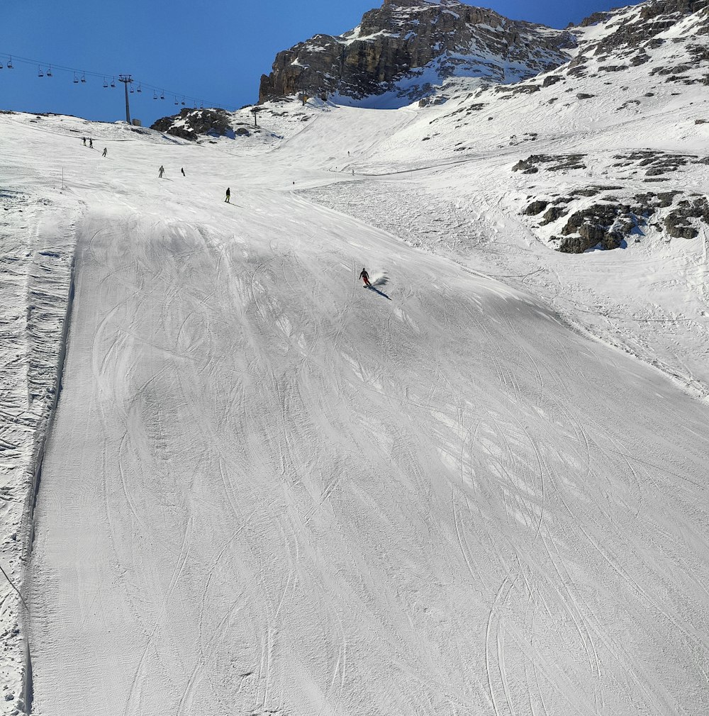 a group of people riding skis down a snow covered slope