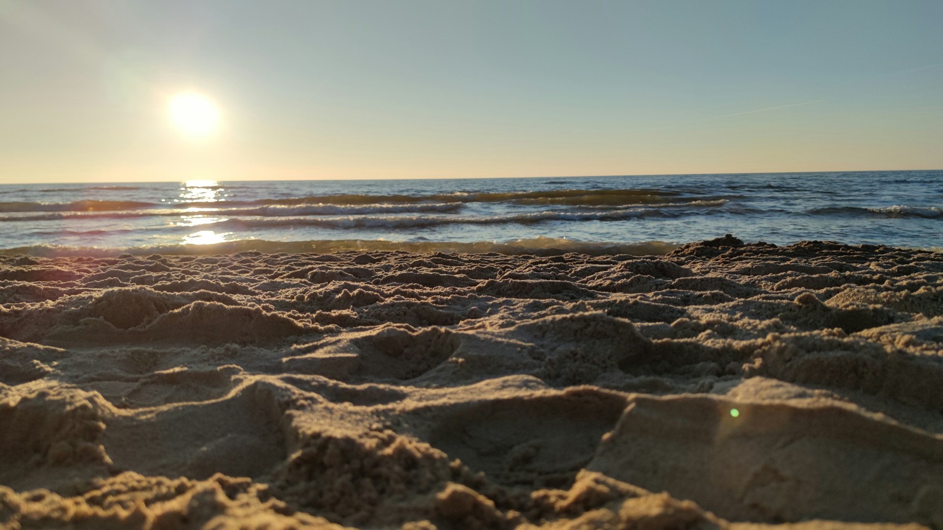 the sun is setting over the ocean on the beach