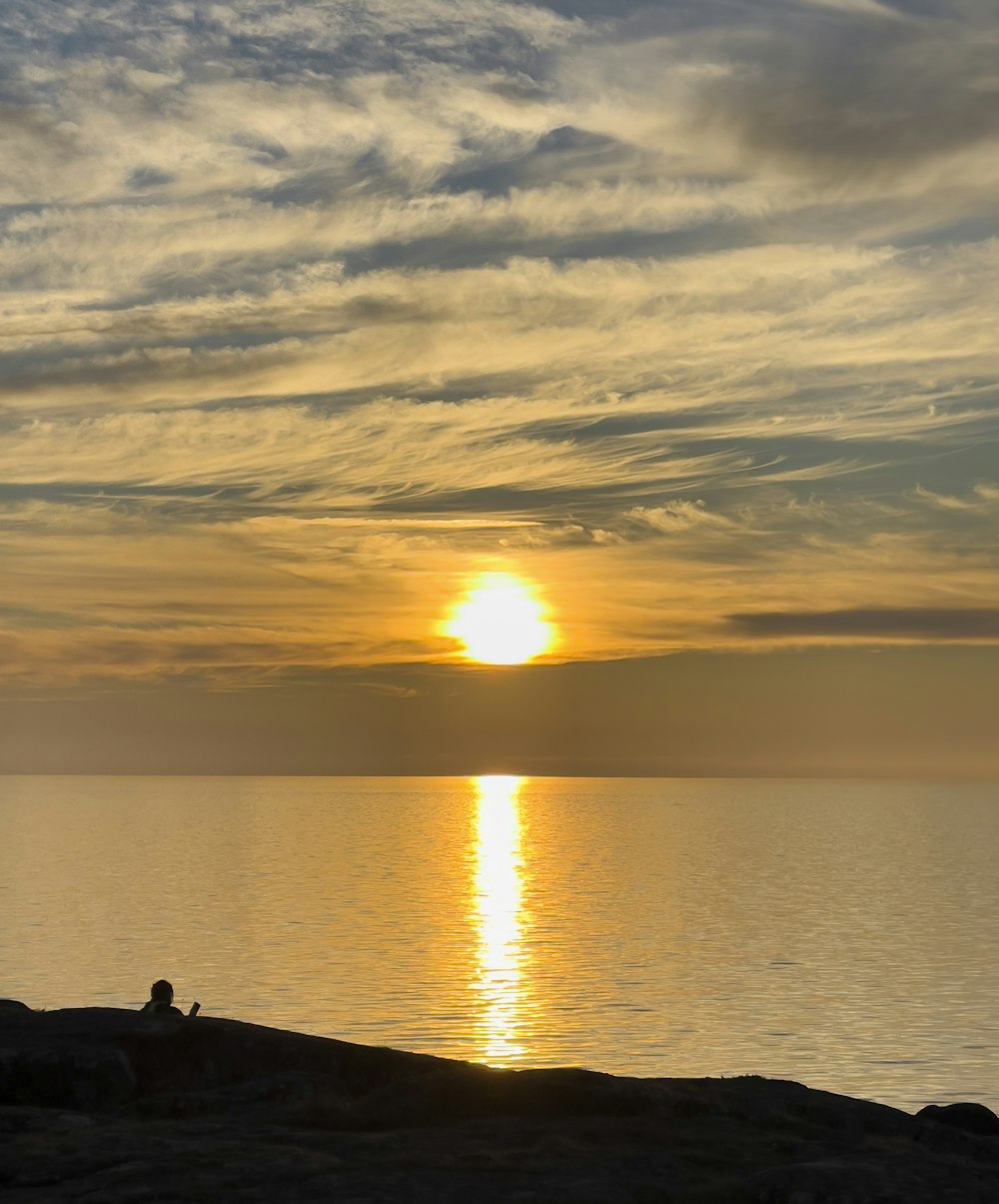 a person sitting on a rock watching the sunset