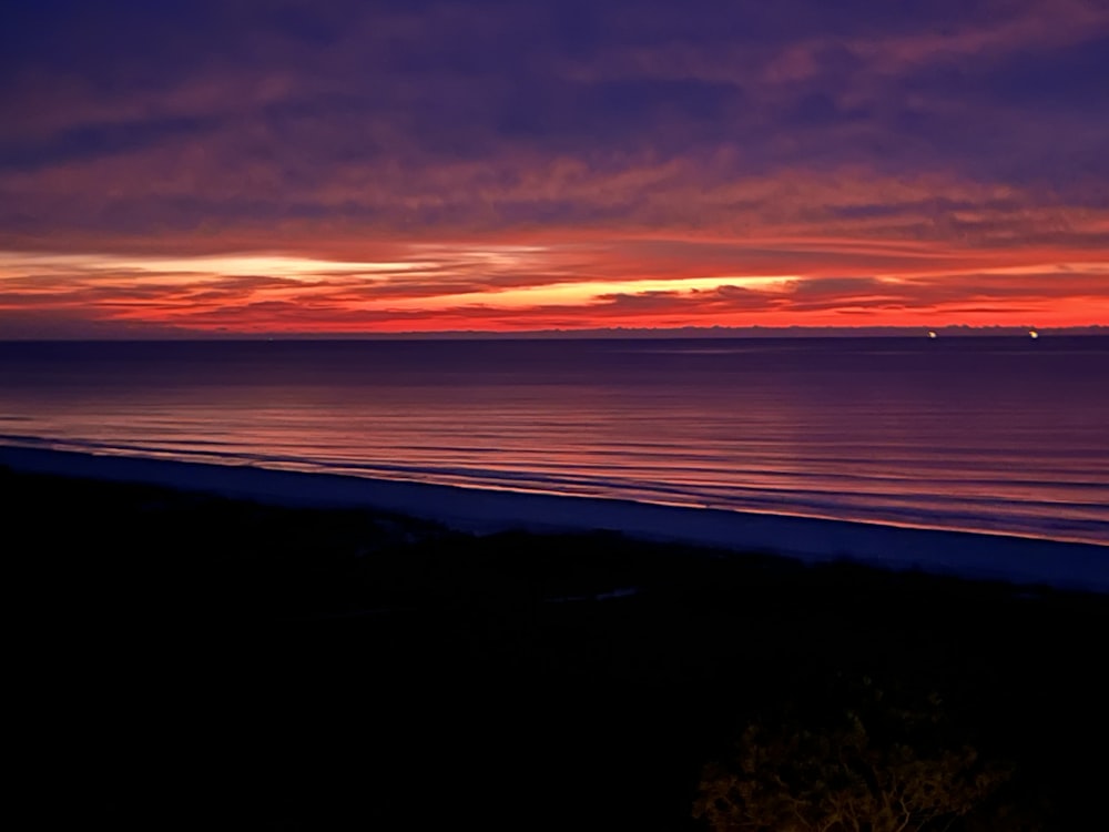 a beautiful sunset over the ocean with a red sky