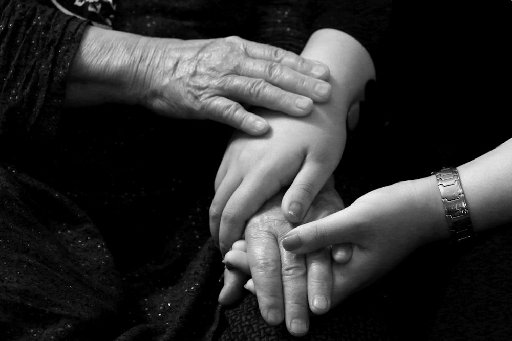 a black and white photo of two people holding hands