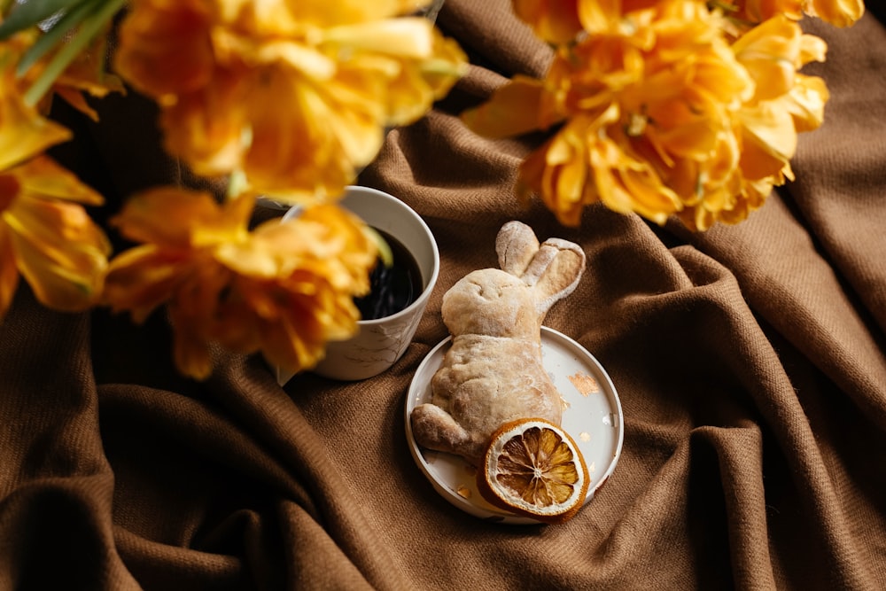 a stuffed animal sitting on a plate next to a cup of coffee