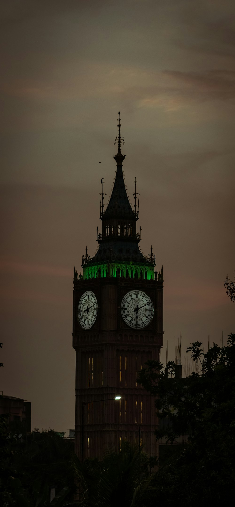 a tall clock tower with a green light on top of it