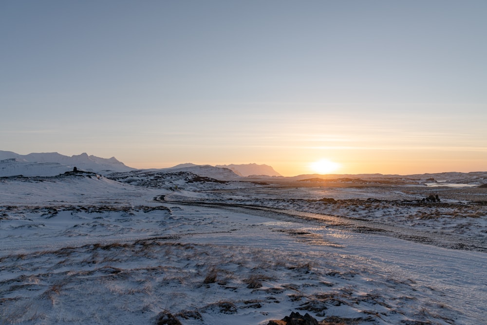 the sun is setting over a snowy landscape