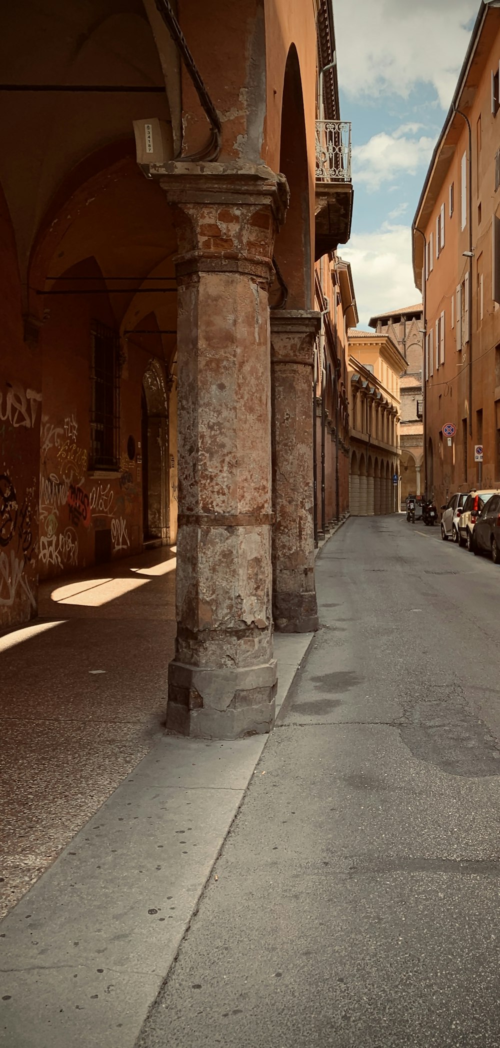 a narrow street with cars parked on both sides