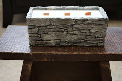 Close-up of vibrant wax blocks and wooden wicks arranged on a rustic wooden table.