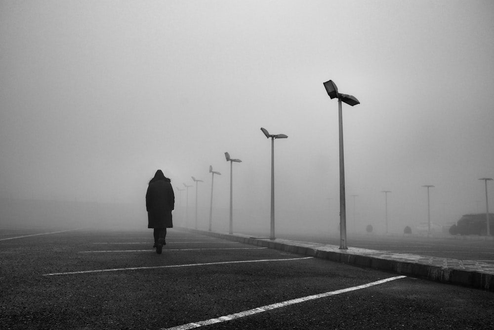 a person walking in a parking lot on a foggy day