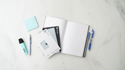 a notebook, pen, and sticky pad on a marble surface