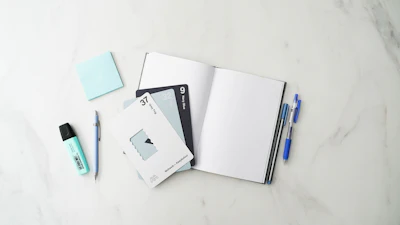 Notebook, pens and sticky notes spread on a marble desk