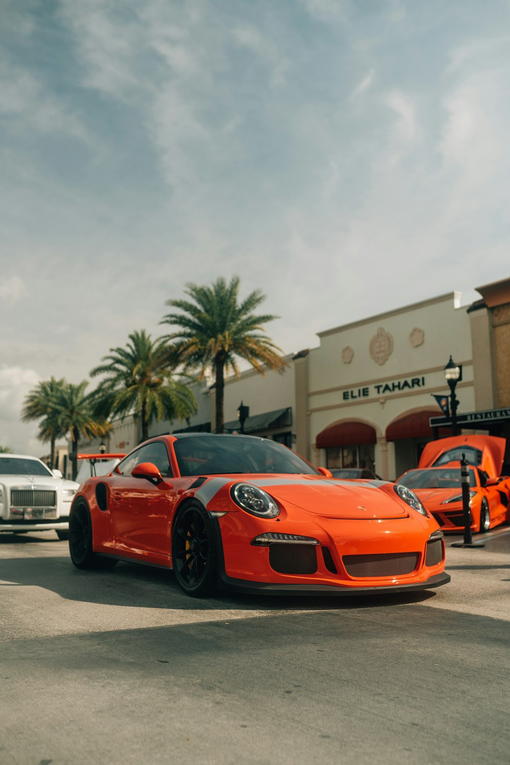 an orange sports car parked in front of a store