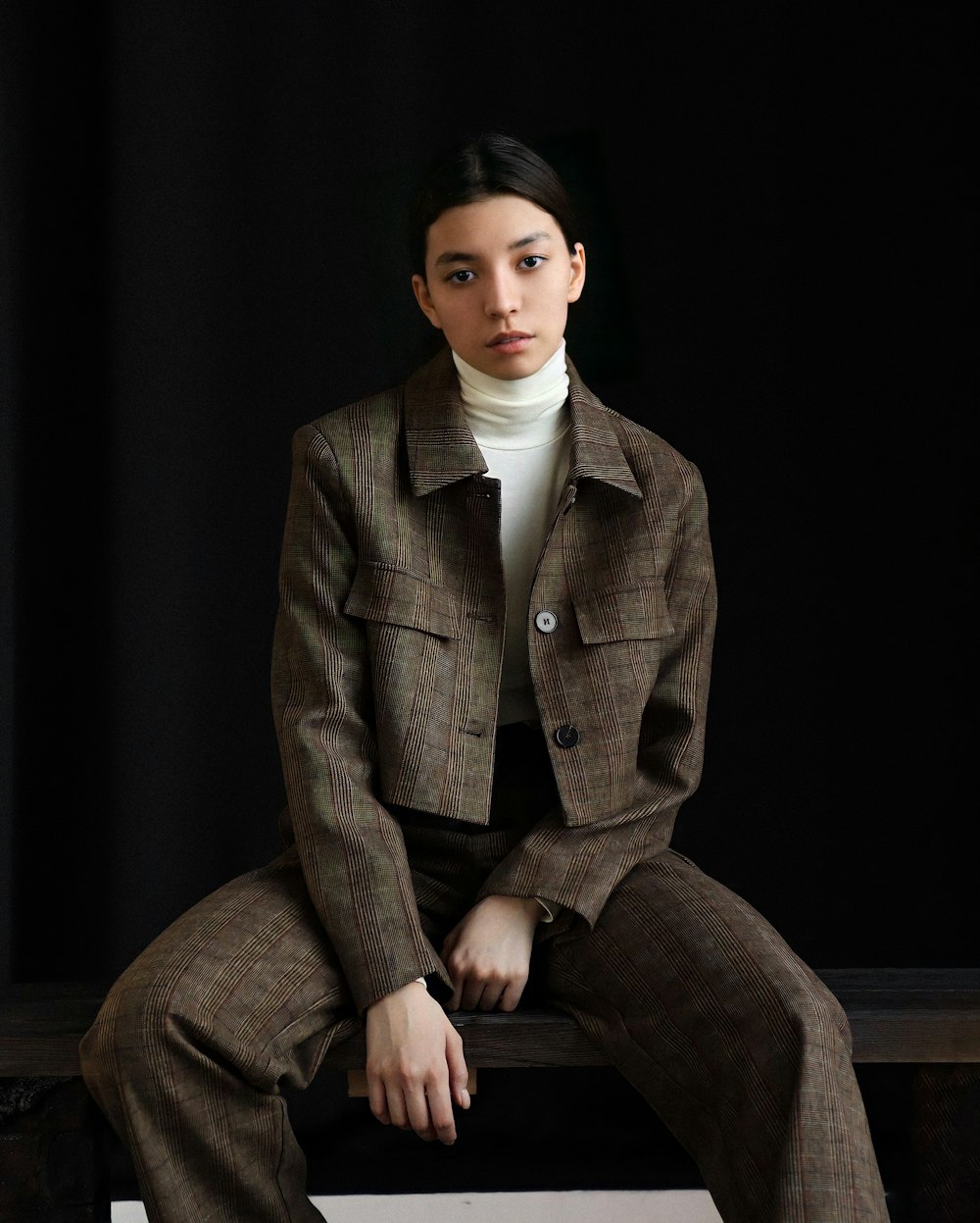 a woman in a brown suit sitting on a bench