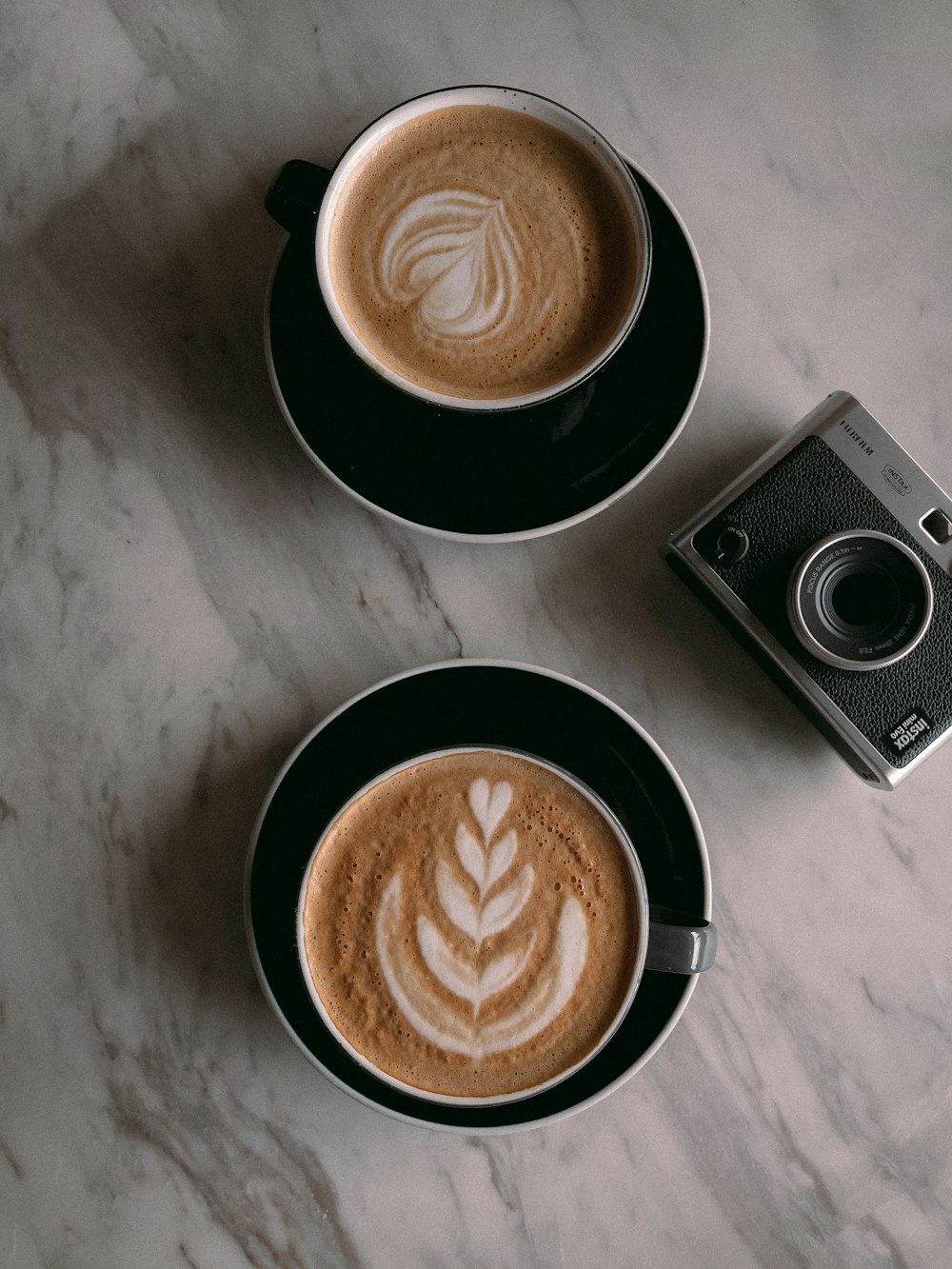 two cups of coffee on a table with a camera