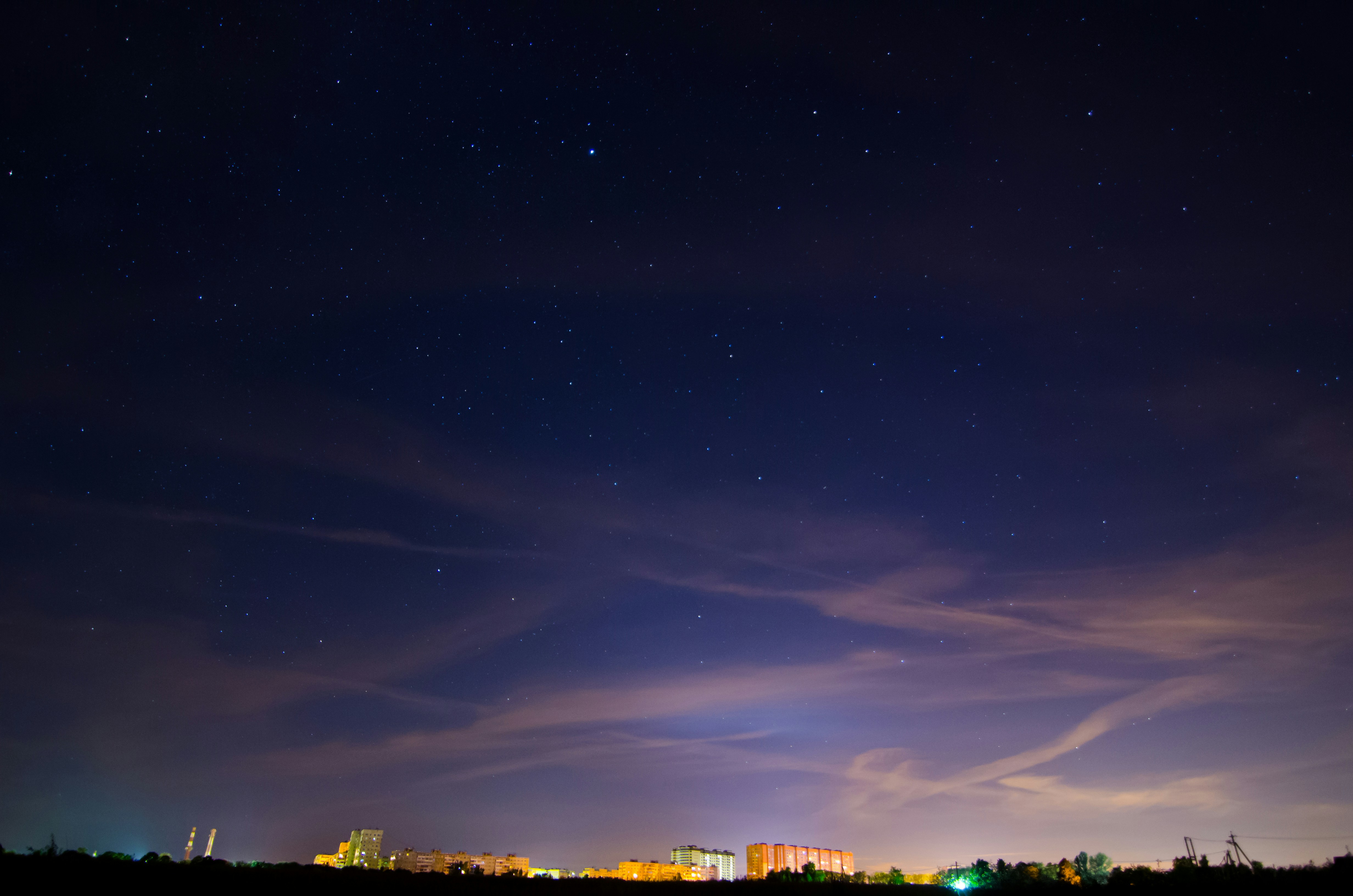 the night sky with stars and clouds over a city