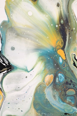 Swirling patterns of colors create an abstract fluid art composition. Shades of teal, mustard, black, and white blend together, forming organic shapes with various textures. Small speckles in different colors are scattered across the canvas, enhancing the dynamic flow of the painting.