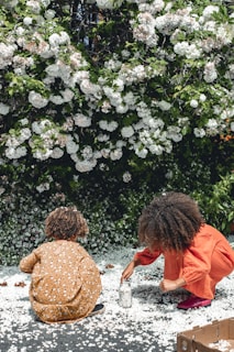 two women sitting on the ground in front of flowers