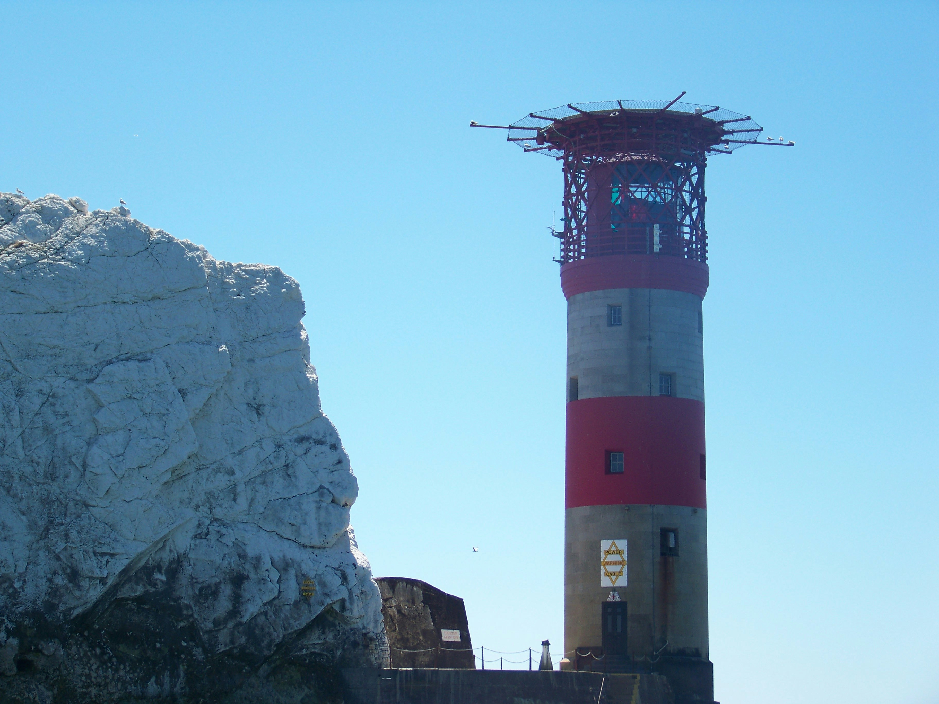 Ein rot-weißer Leuchtturm neben einem großen Felsen