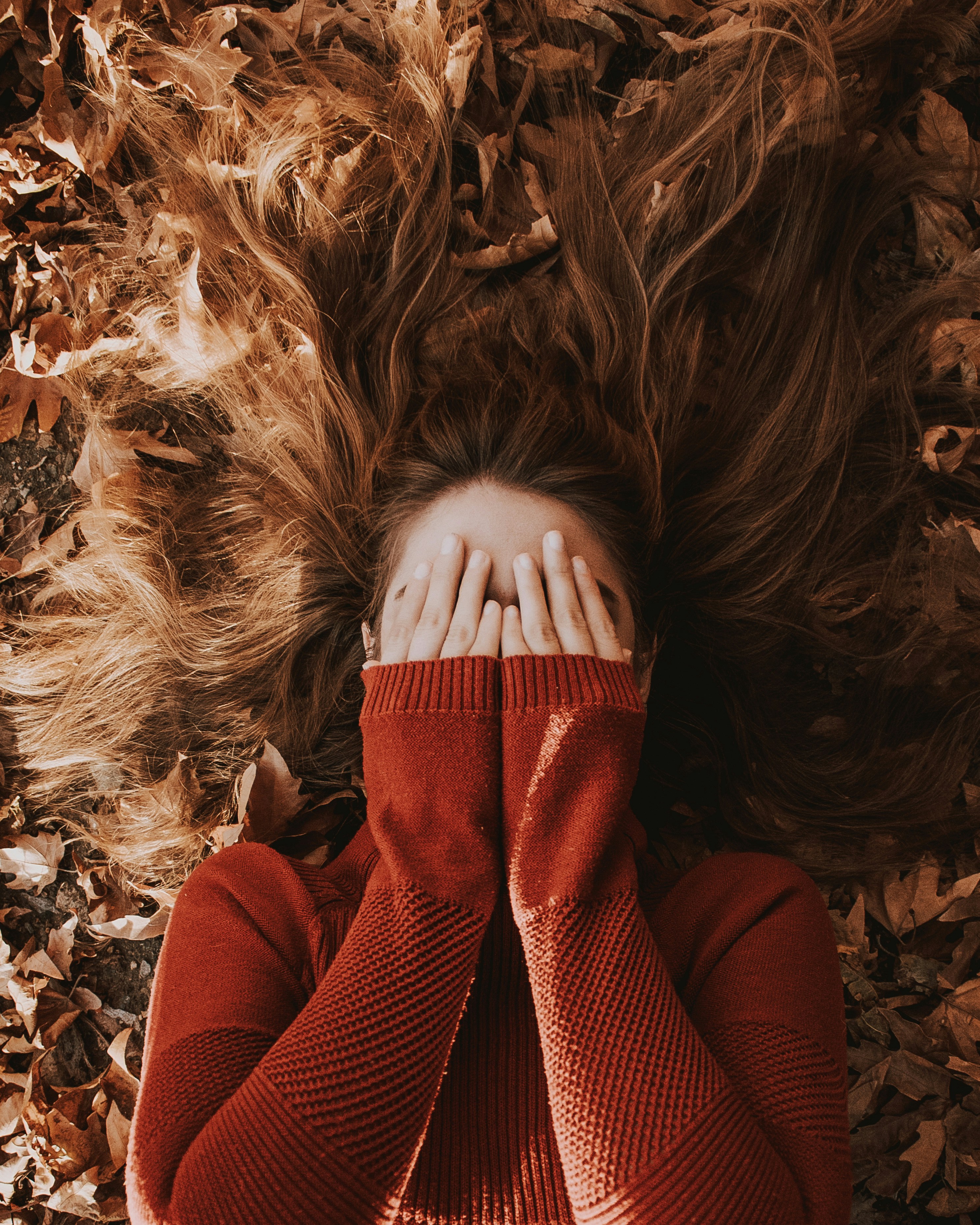 a woman laying on top of a pile of leaves