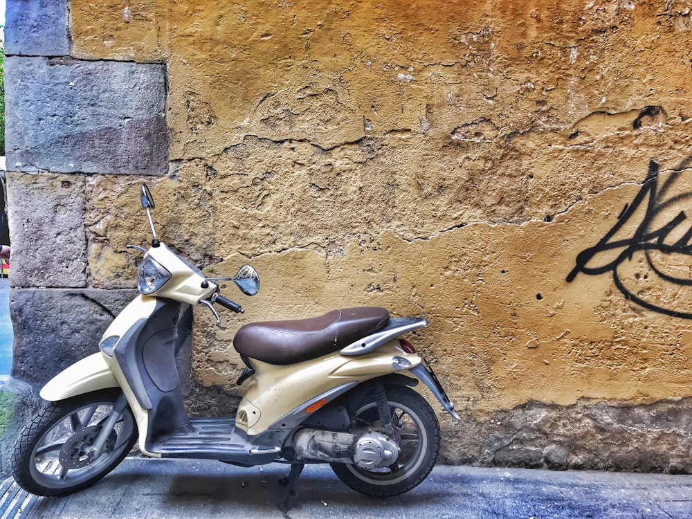 a scooter parked next to a wall with graffiti on it