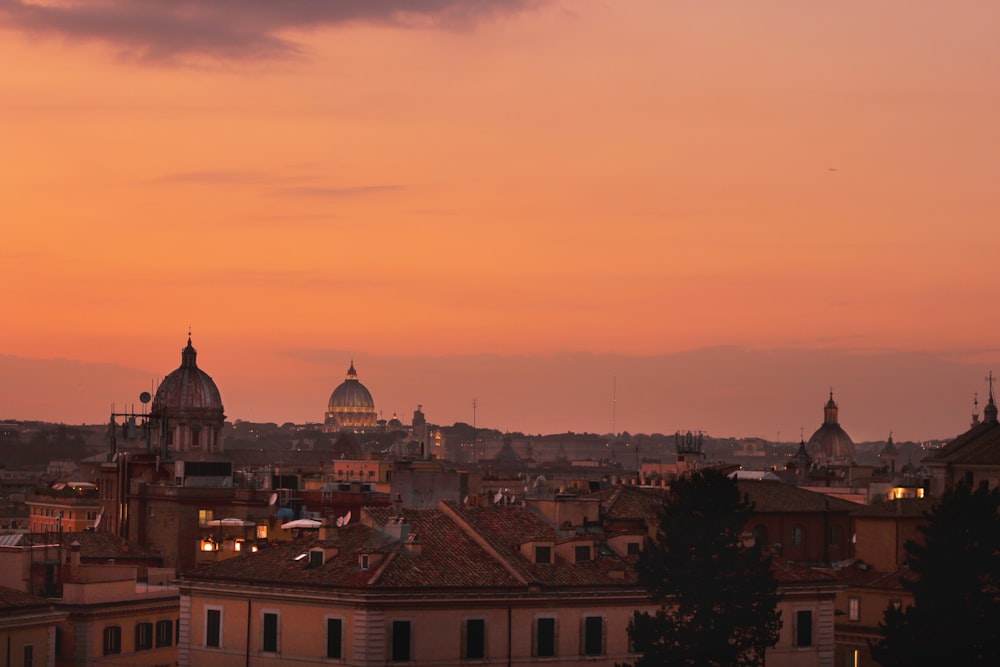 a sunset view of a city with buildings and a dome