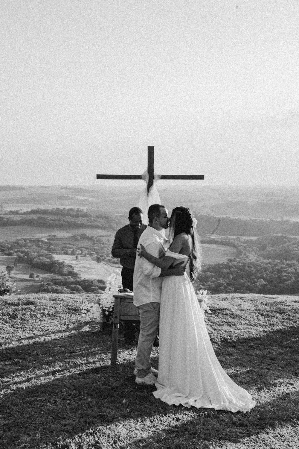 a man and woman standing in front of a cross