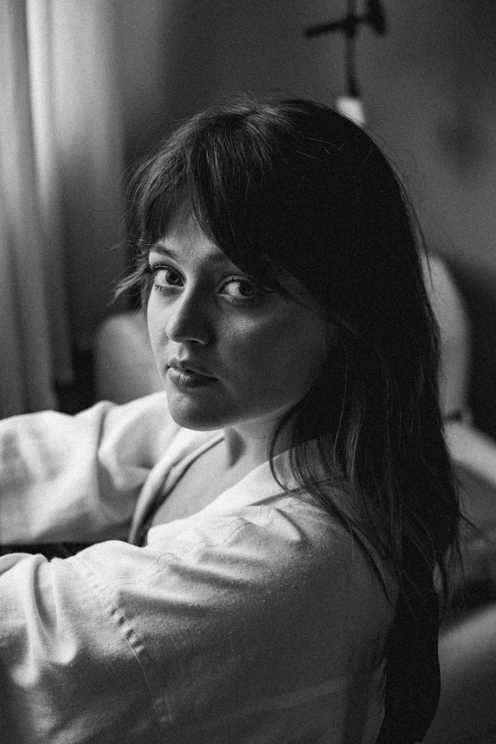 a black and white photo of a woman sitting on a bed