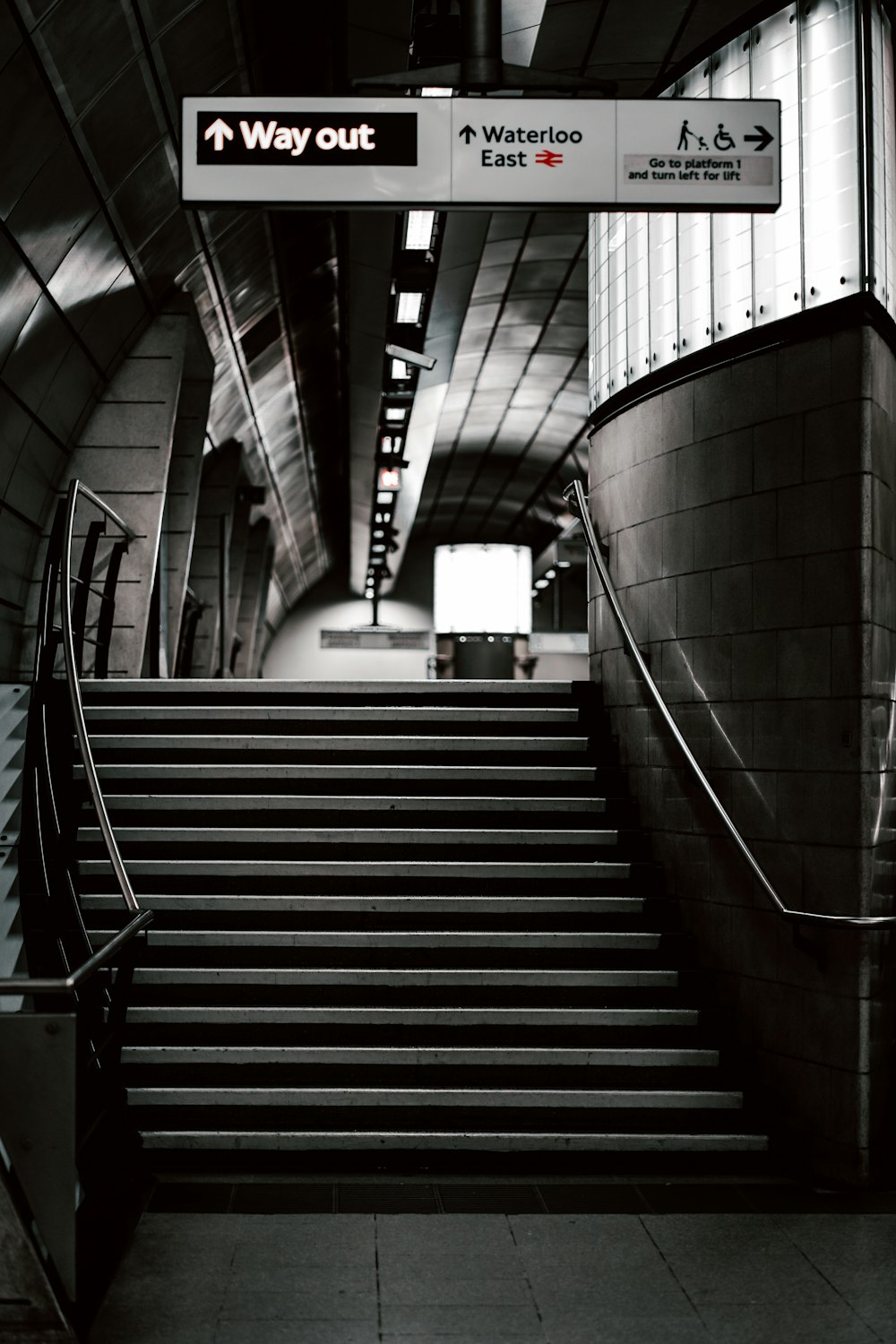 a black and white photo of an escalator and stairs
