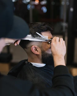 a man cutting another mans hair with a pair of scissors