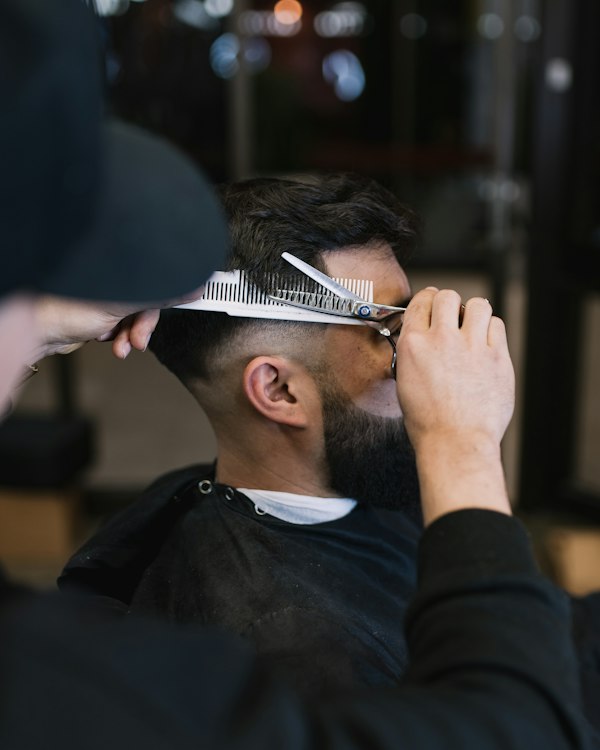 Close-up of barber cutting hair with a comb and thinning scissors
