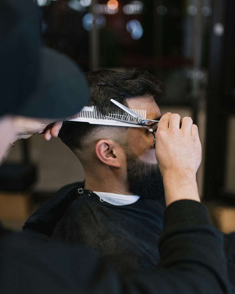 a man cutting another mans hair with a pair of scissors