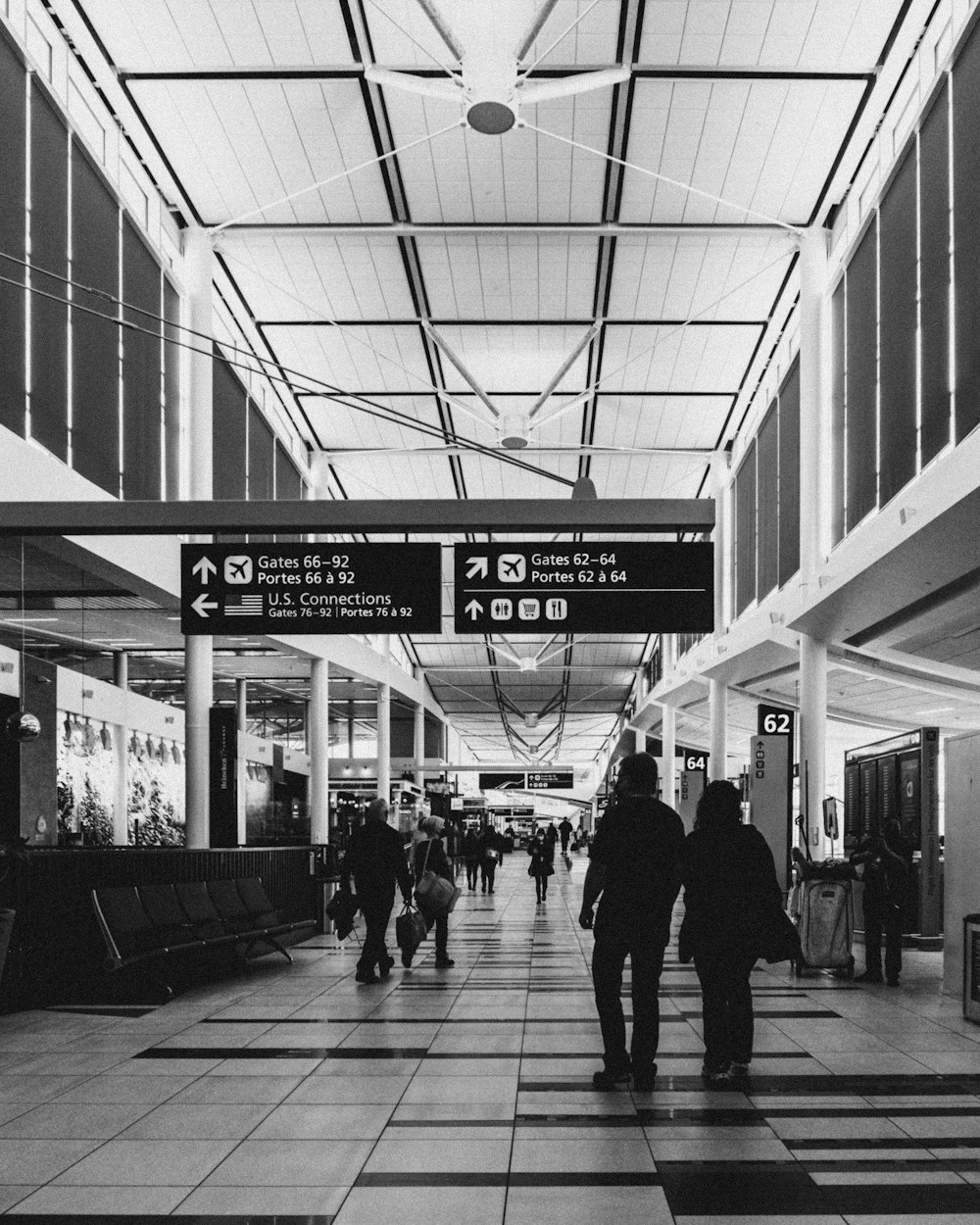 Una foto in bianco e nero di persone che camminano attraverso un aeroporto