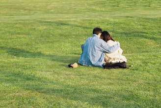 a couple of people sitting on top of a lush green field