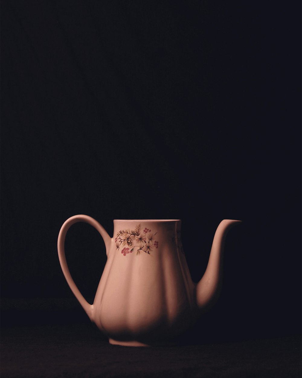 a pink teapot with a floral design on it