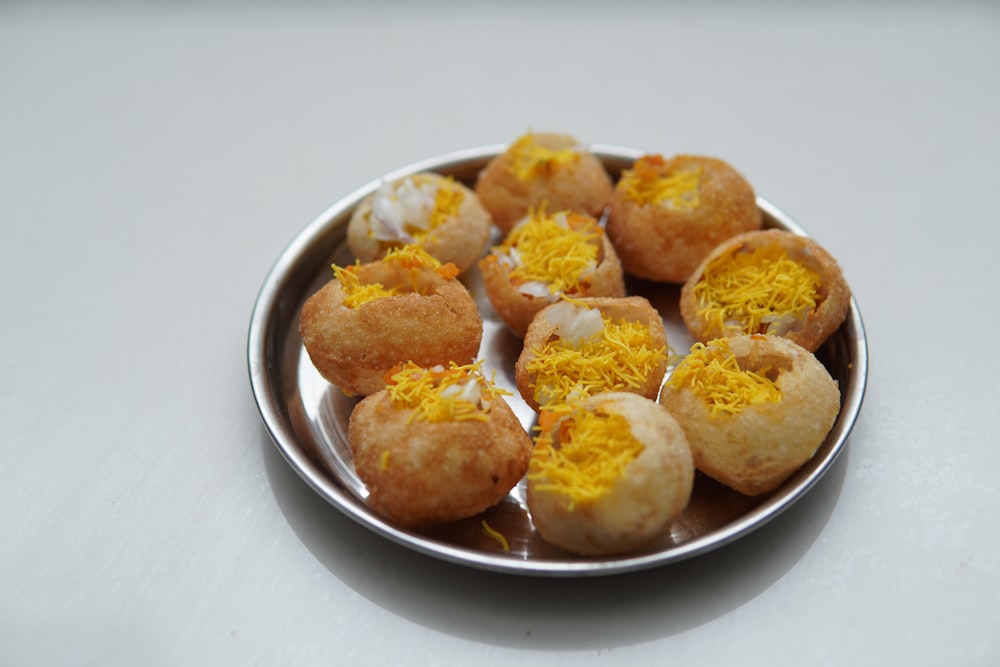 a metal plate filled with small pastries covered in orange and white icing