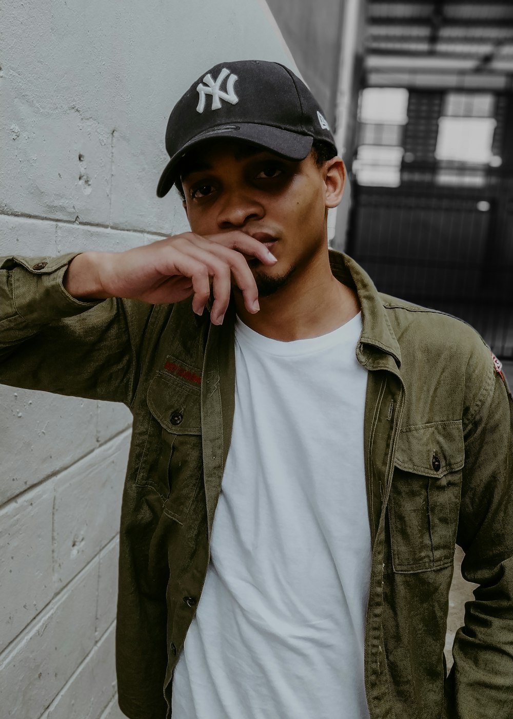 a young man smoking a cigarette in front of a wall